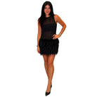 A woman modeling a black sleeveless dress with a sheer mesh bodice and a short black feathered skirt, posed against a plain white background.