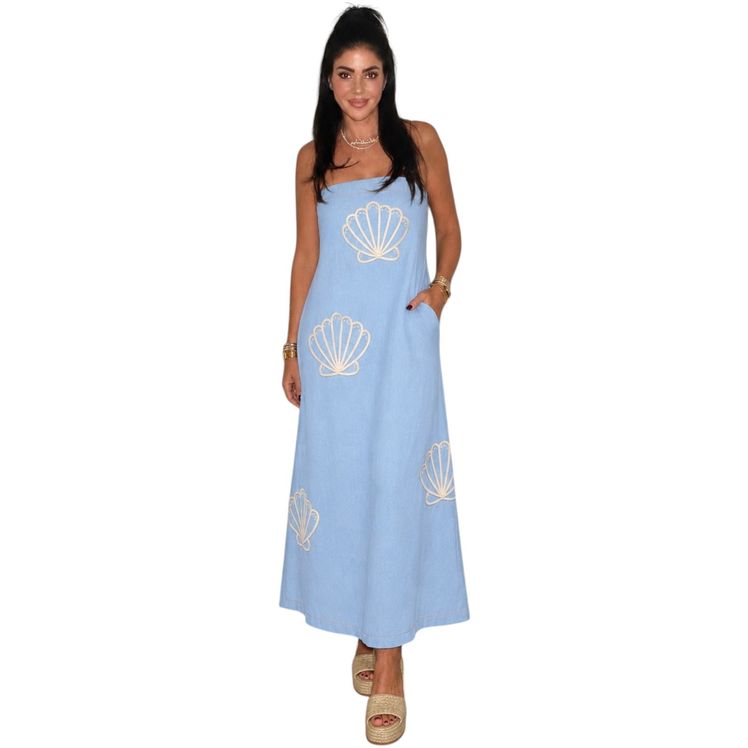 Woman wearing a light blue dress with shell patterns on a white background