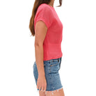 Person wearing a pink knitted top and denim shorts on a white background