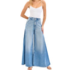 Woman wearing a white top and blue wide-leg jeans on a white background