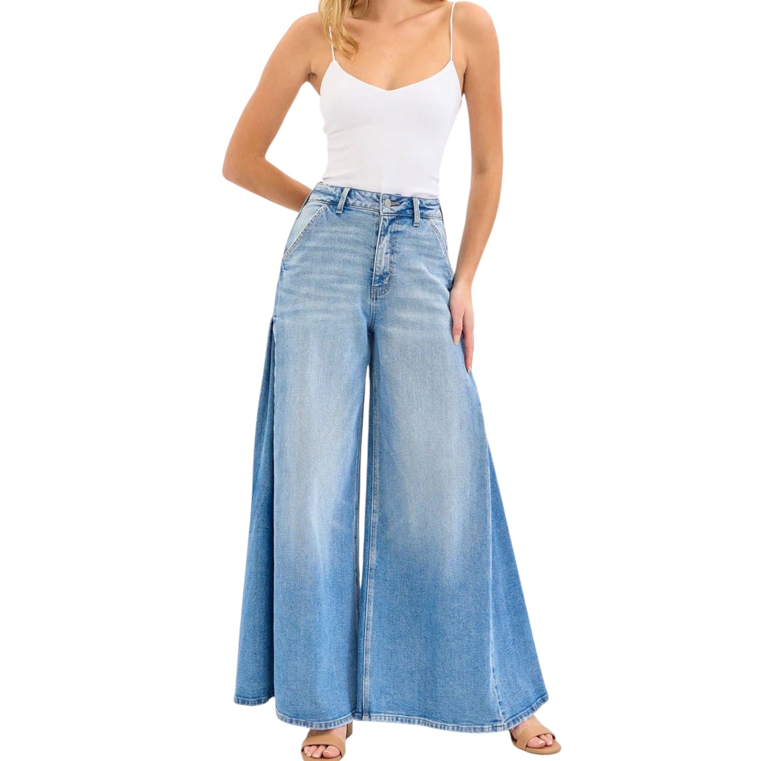 Woman wearing a white top and blue wide-leg jeans on a white background