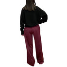 Person wearing a black sweater and maroon pants on a white background
