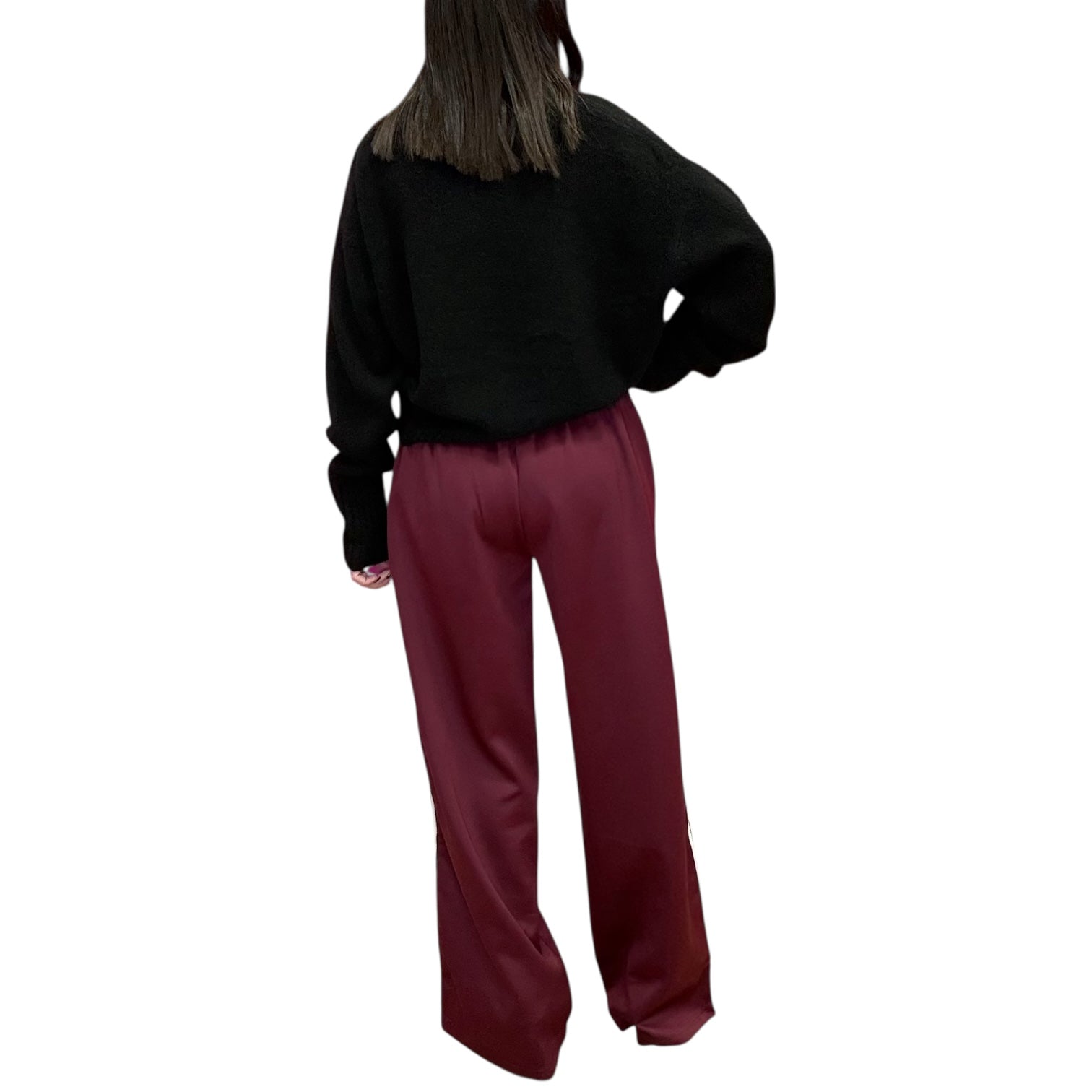 Person wearing a black sweater and maroon pants on a white background