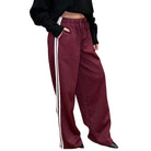 Maroon track pants with white stripes worn by a person on a white background