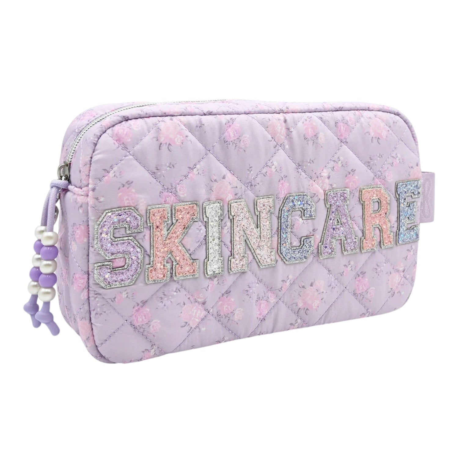 A light purple quilted cosmetic pouch with a floral pattern, featuring the word 'SKINCARE' spelled out in glittery, pastel-colored letters across the front. The pouch has a zipper closure with a purple and white beaded tassel zipper pull on the left side.