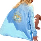 Light blue gauze shirt with a gold eye design on a white background