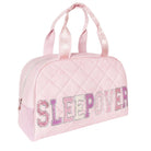 A light pink quilted duffel bag with 'SLEEP OVER' written across the front in glittery pink, purple, and white letters, featuring two top handles on a white background.