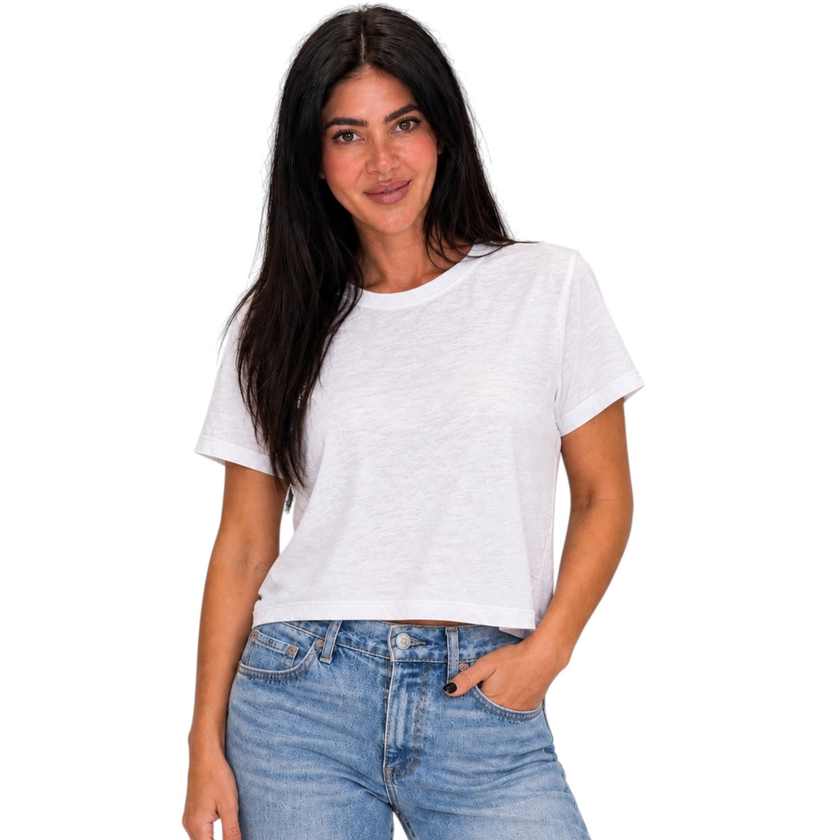 A woman with long dark hair wearing a white short-sleeve crop top and blue jeans, standing against a plain white background.