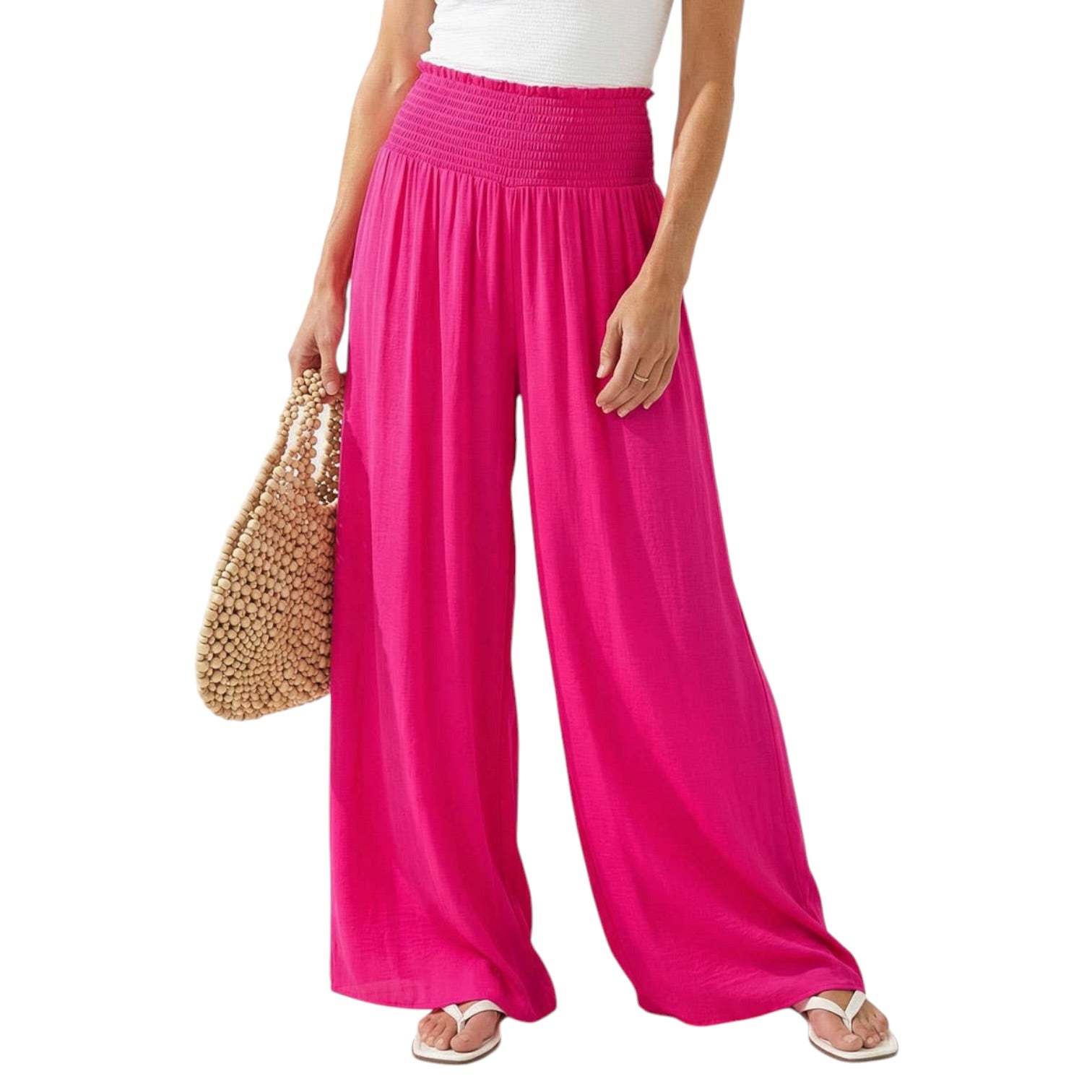 Person wearing bright pink wide-leg pants holding a straw bag on a white background