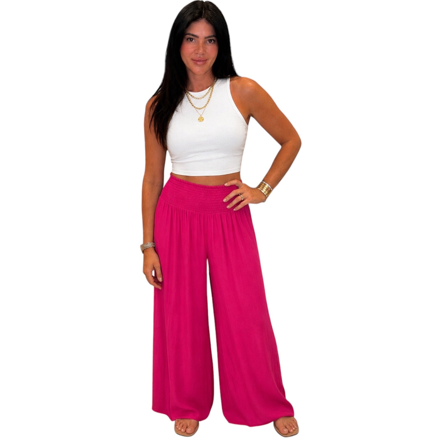 Woman wearing a white top and bright pink pants on a white background