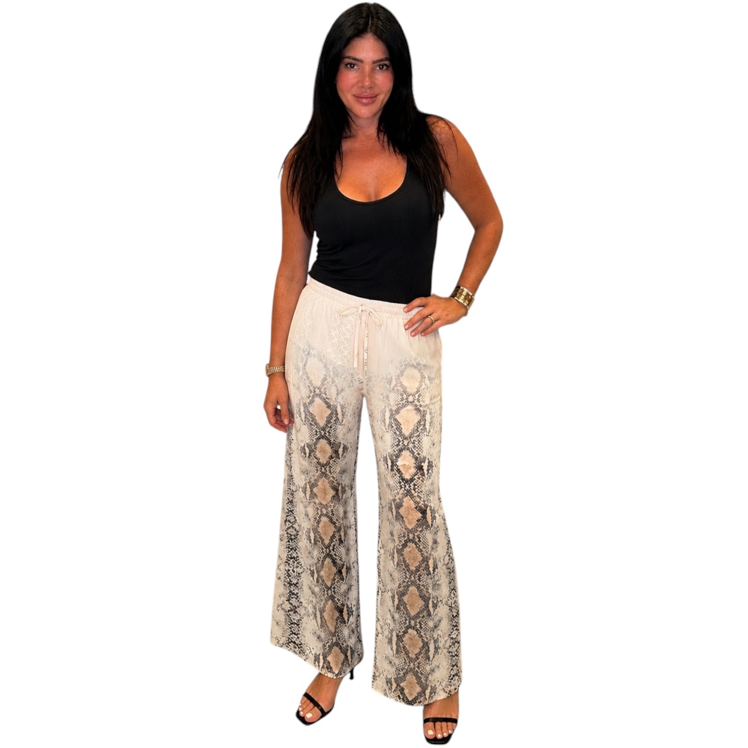 Woman wearing a black top and patterned beige pants on a white background