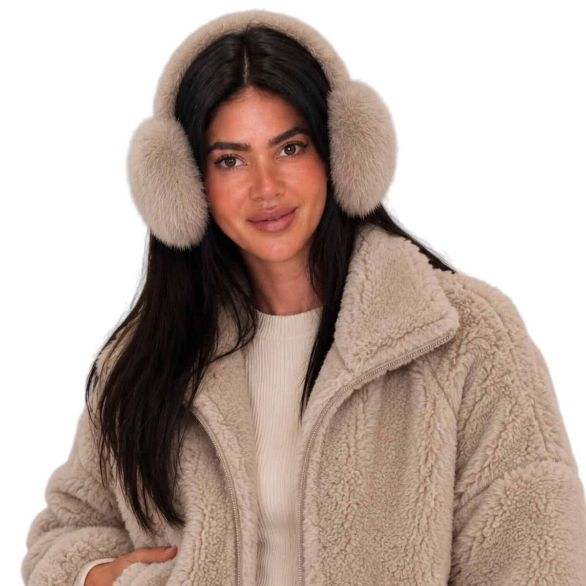 A woman wearing fluffy faux-fur earmuffs in a light beige color, paired with a matching beige sherpa fleece jacket and a cream ribbed sweater, set against a solid white background.