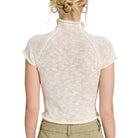 Back view of a person wearing a white knit top on a white background