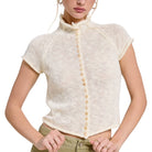 Woman wearing a cream-colored knitted cardigan with buttons on a white background
