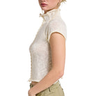 Woman wearing a white knit top with a plain background