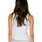 Person wearing a white sleeveless top on a plain background