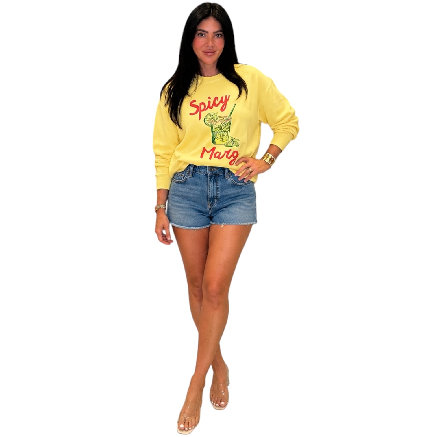 Woman wearing a yellow sweatshirt with text and denim shorts on a white background
