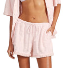 Person wearing light pink shorts and a matching top on a white background