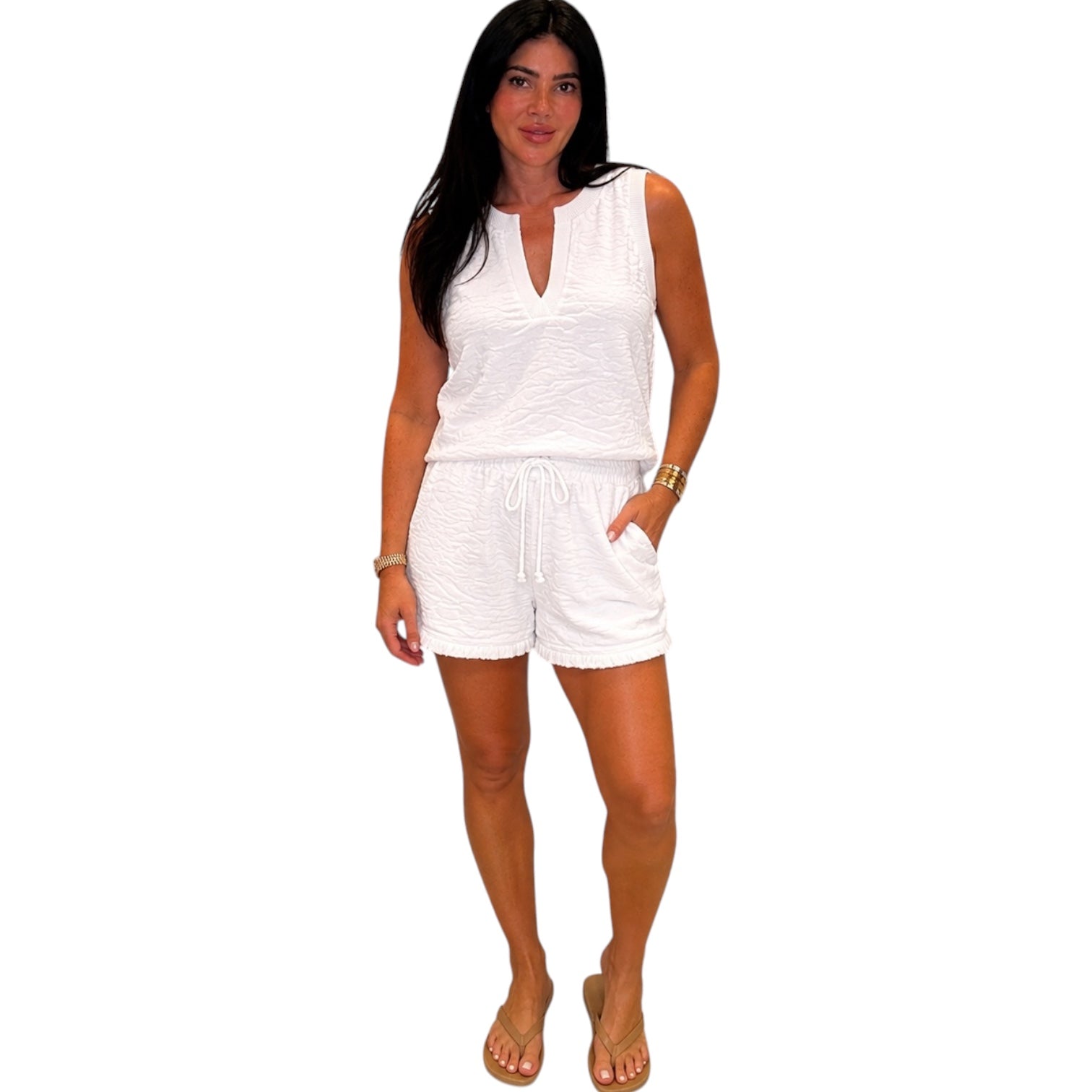 Woman wearing a white sleeveless top and shorts set on a white background
