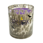 A 'Spooky' scented candle in a clear glass jar with a textured, honeycomb-like pattern. The candle features a purple wax top with a wick and a purple label, decorated with black bats, a yellow crescent moon, and the word 'SPOOKY' in purple and yellow lettering.