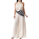 White halter neck jumpsuit with a black and white striped belt on a white background