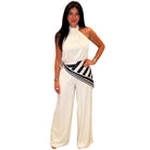 Woman wearing a white halter neck jumpsuit with a striped belt on a white background