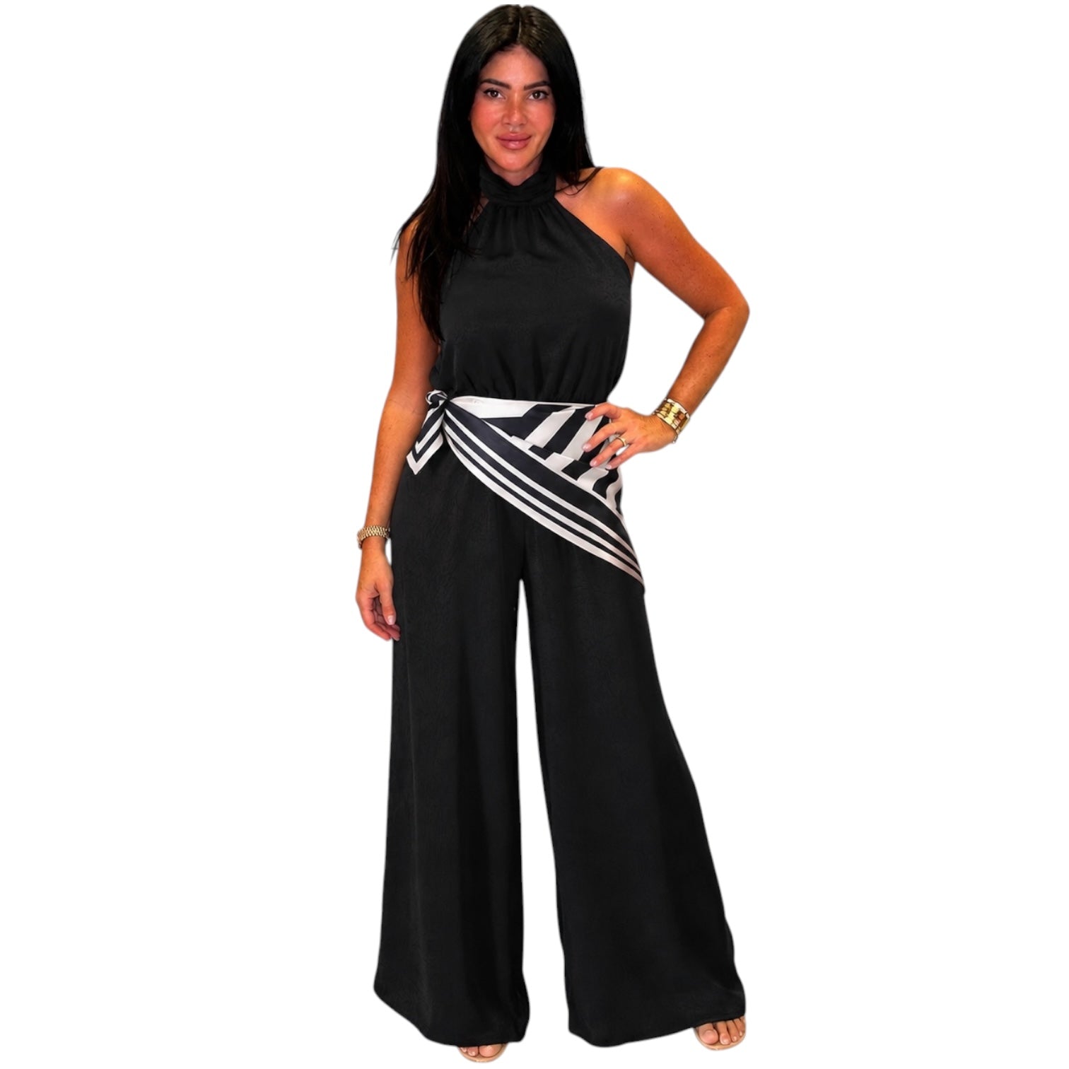 Black halter jumpsuit with a striped sash on a white background