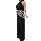 Black halter jumpsuit with a striped sash on a white background