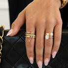Hand with gold rings on a black quilted handbag