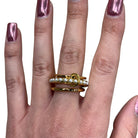 Gold ring with small stones on a hand with pink nail polish