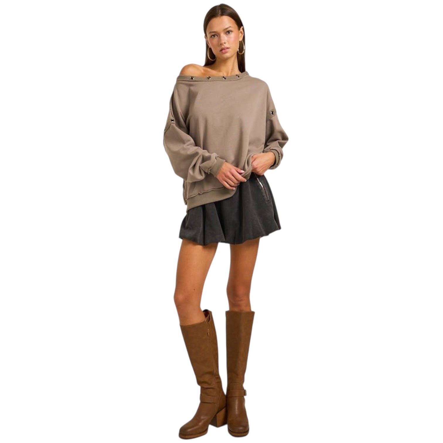 Woman wearing a beige sweater, black skirt, and brown knee-high boots on a white background