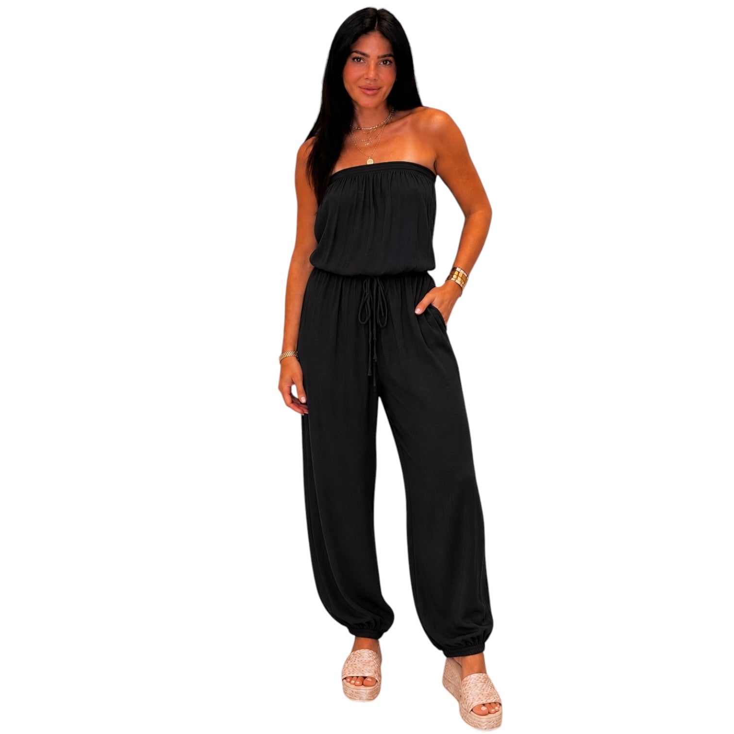 Woman wearing a black strapless jumpsuit on a white background