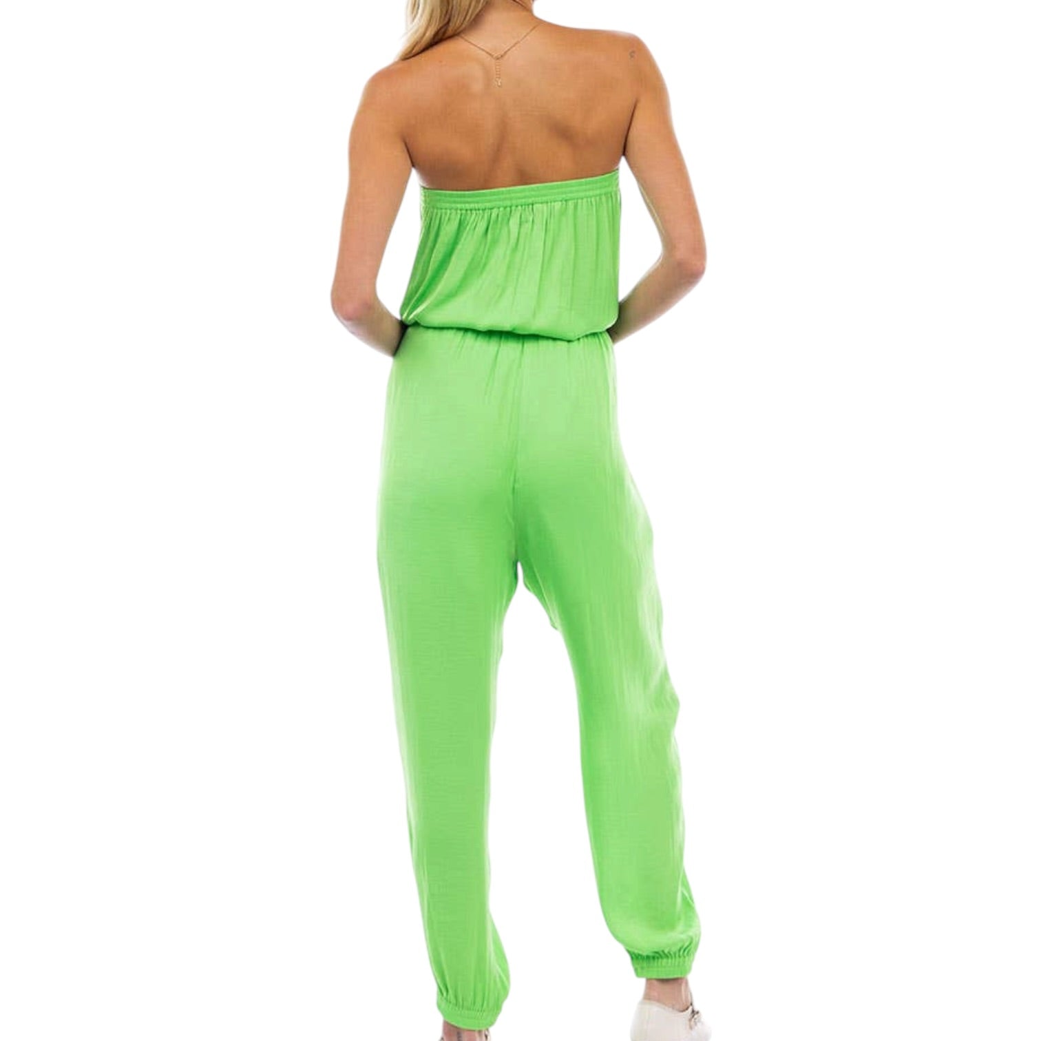 Woman wearing a bright green strapless jumpsuit on a white background