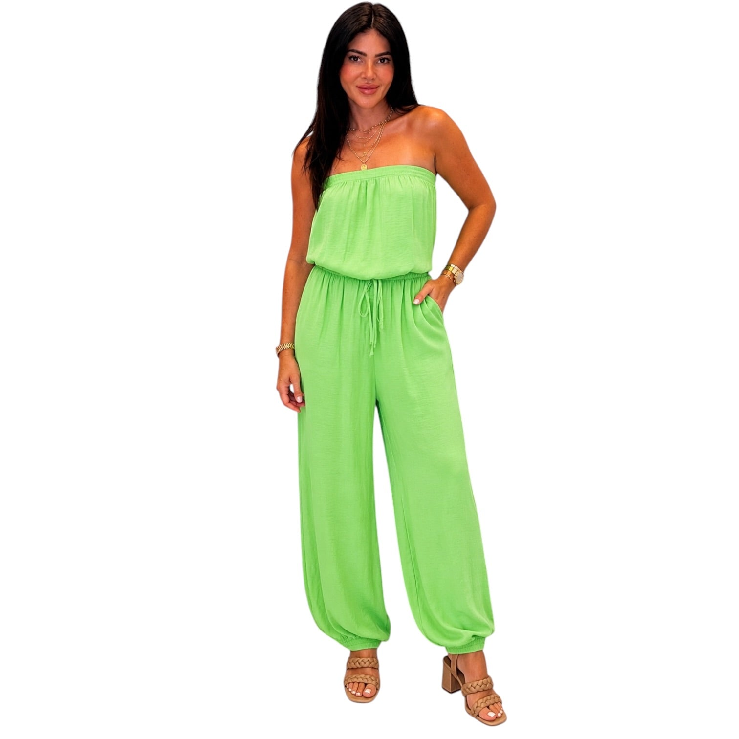 Woman wearing a bright green strapless jumpsuit on a white background