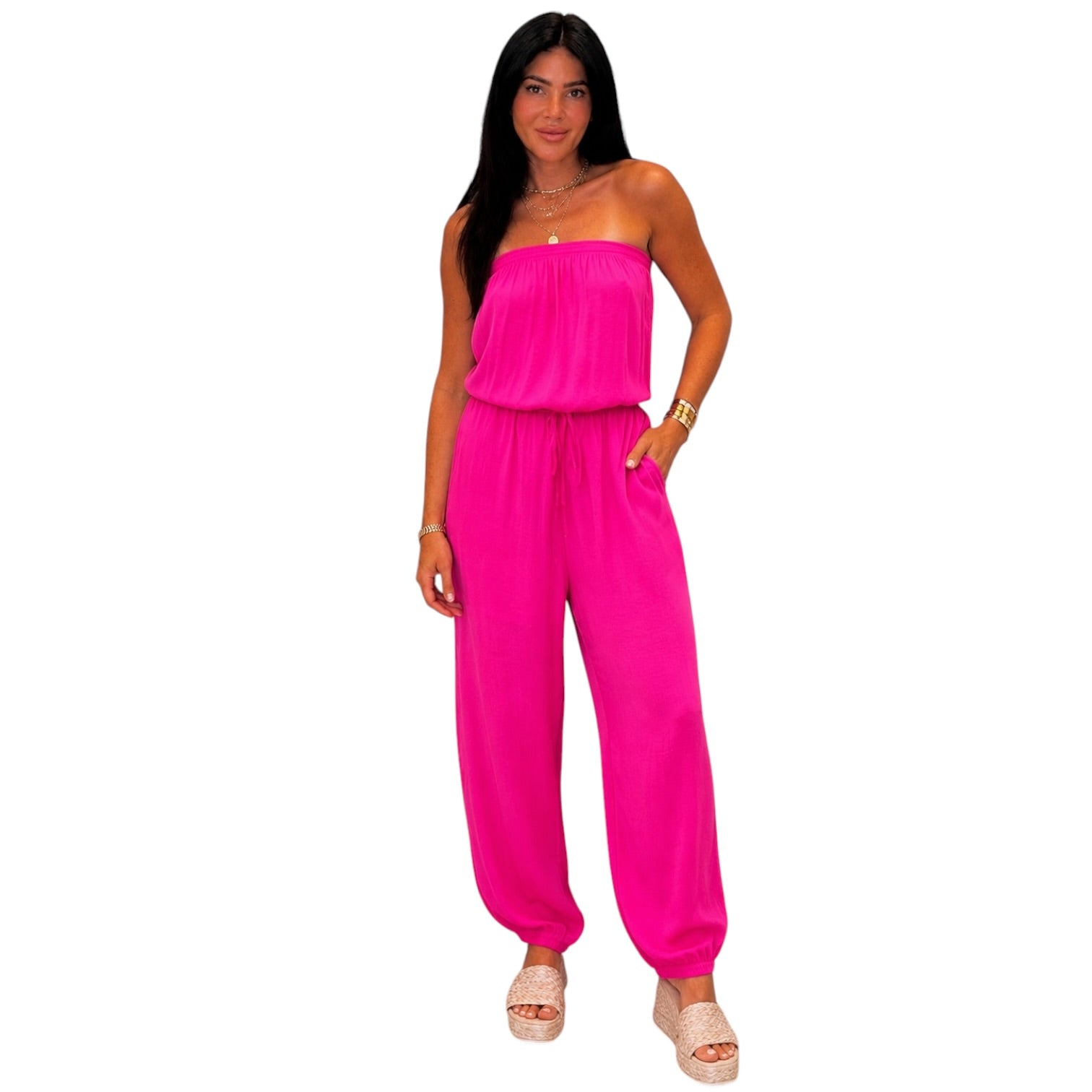 Woman wearing a bright pink strapless jumpsuit on a white background