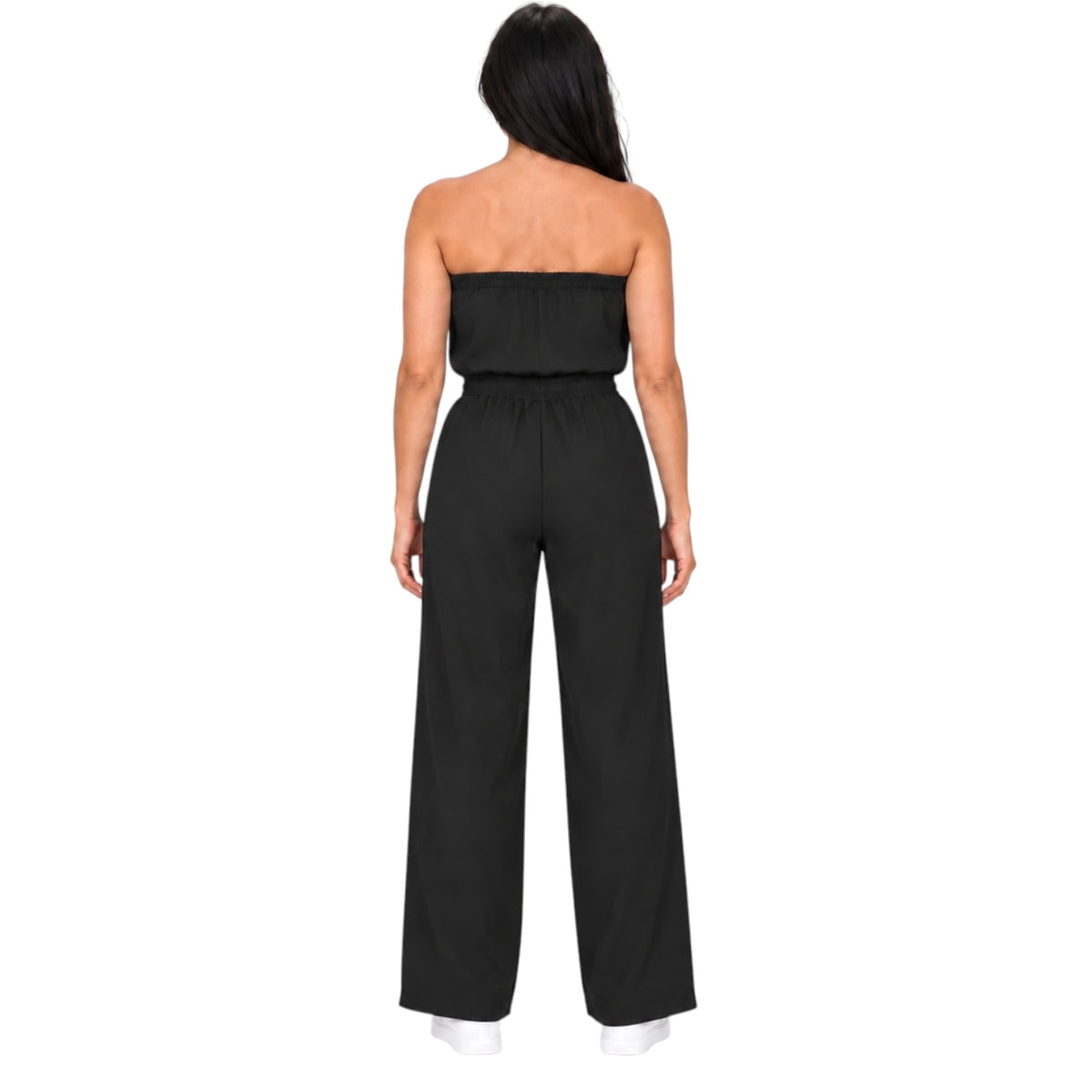 A woman viewed from the back wearing a black strapless jumpsuit with wide legs and a high waist, standing against a plain white background.