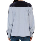 A person shown from the back wearing a long-sleeve button-up shirt with a light blue and white vertical stripe body and contrasting dark navy shoulder yokes and cuffs, paired with blue jeans against a plain white background.