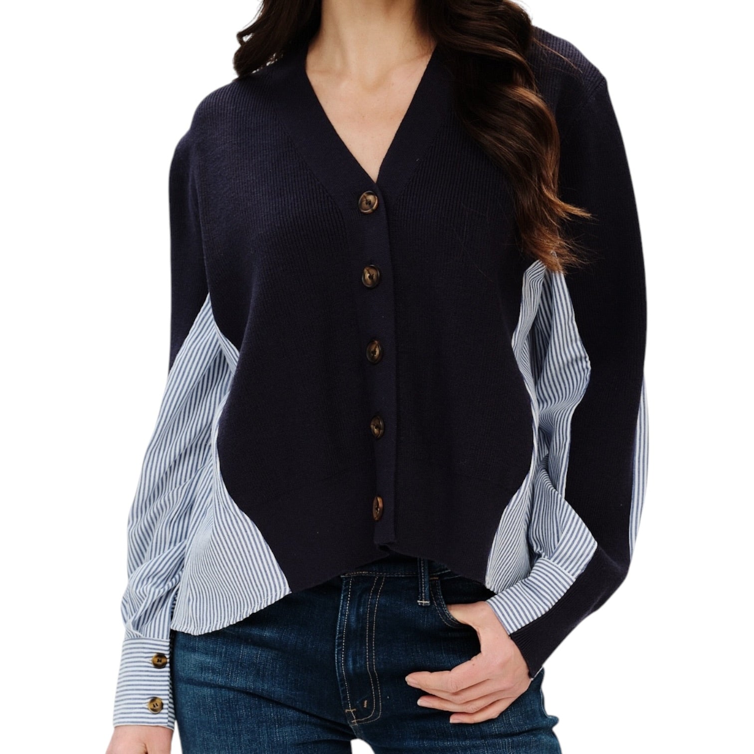 A woman wearing a navy cardigan with striped blue and white sleeves and brown buttons, paired with dark blue jeans, against a plain white background.