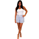 Woman wearing a white tank top and blue striped shorts on a white background