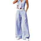 Person wearing a blue and white striped outfit with wide-leg pants on a white background