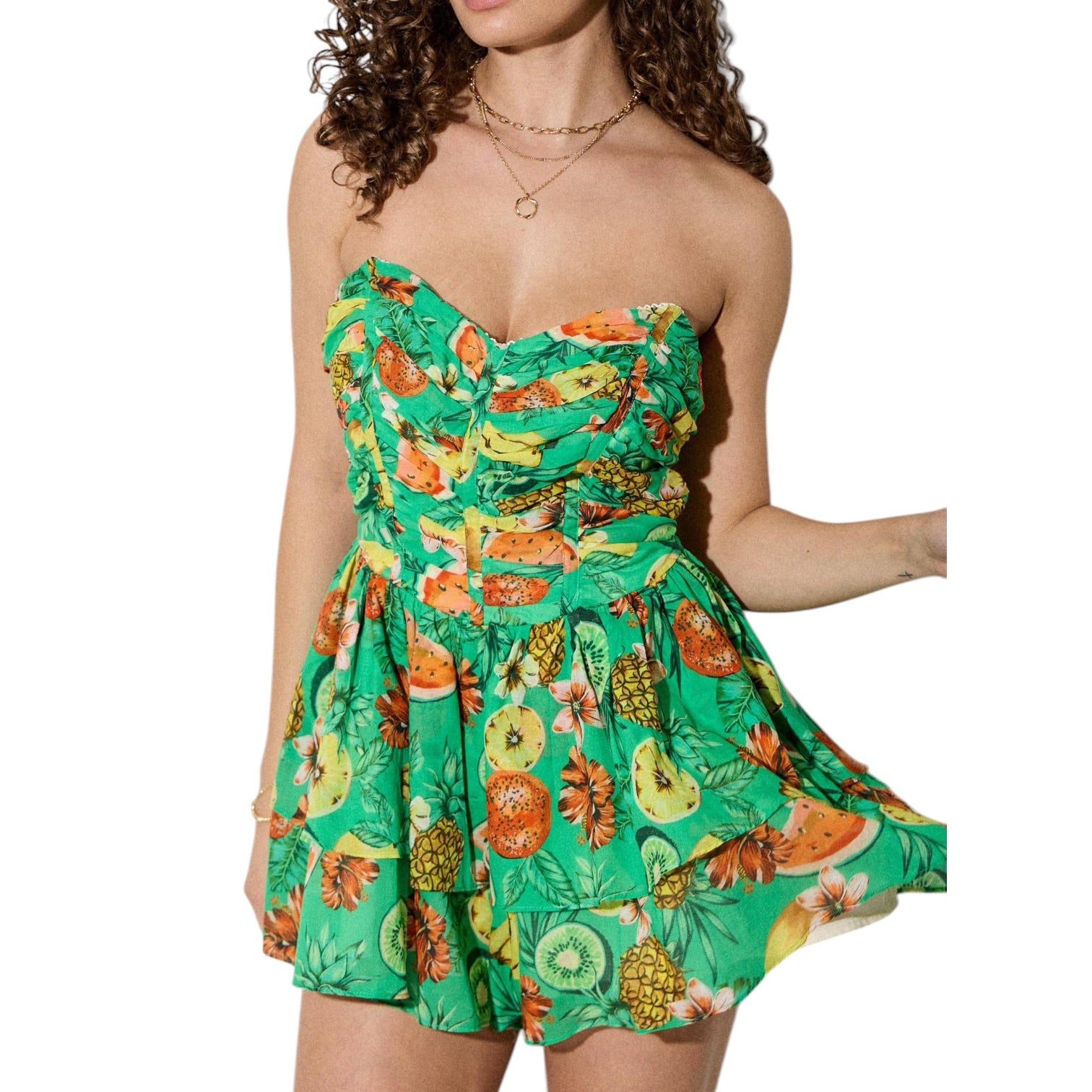 Woman wearing a green romper with fruit pattern on a white background