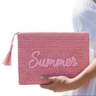 Pink clutch bag with 'Summer' text held by a person against a white background