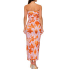Woman wearing a strapless floral dress with orange and pink pattern on a white background