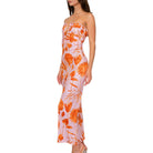 Woman wearing a strapless dress with orange floral pattern on a white background