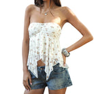 Woman wearing a white floral strapless top and denim shorts on a white background