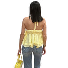 Woman wearing a yellow top and blue jeans, holding a yellow bag on a white background