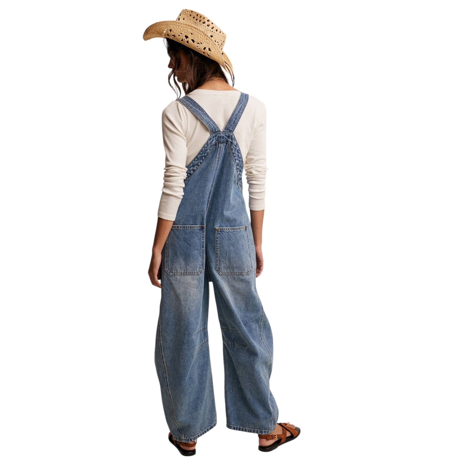 Person wearing denim overalls and a straw hat on a white background