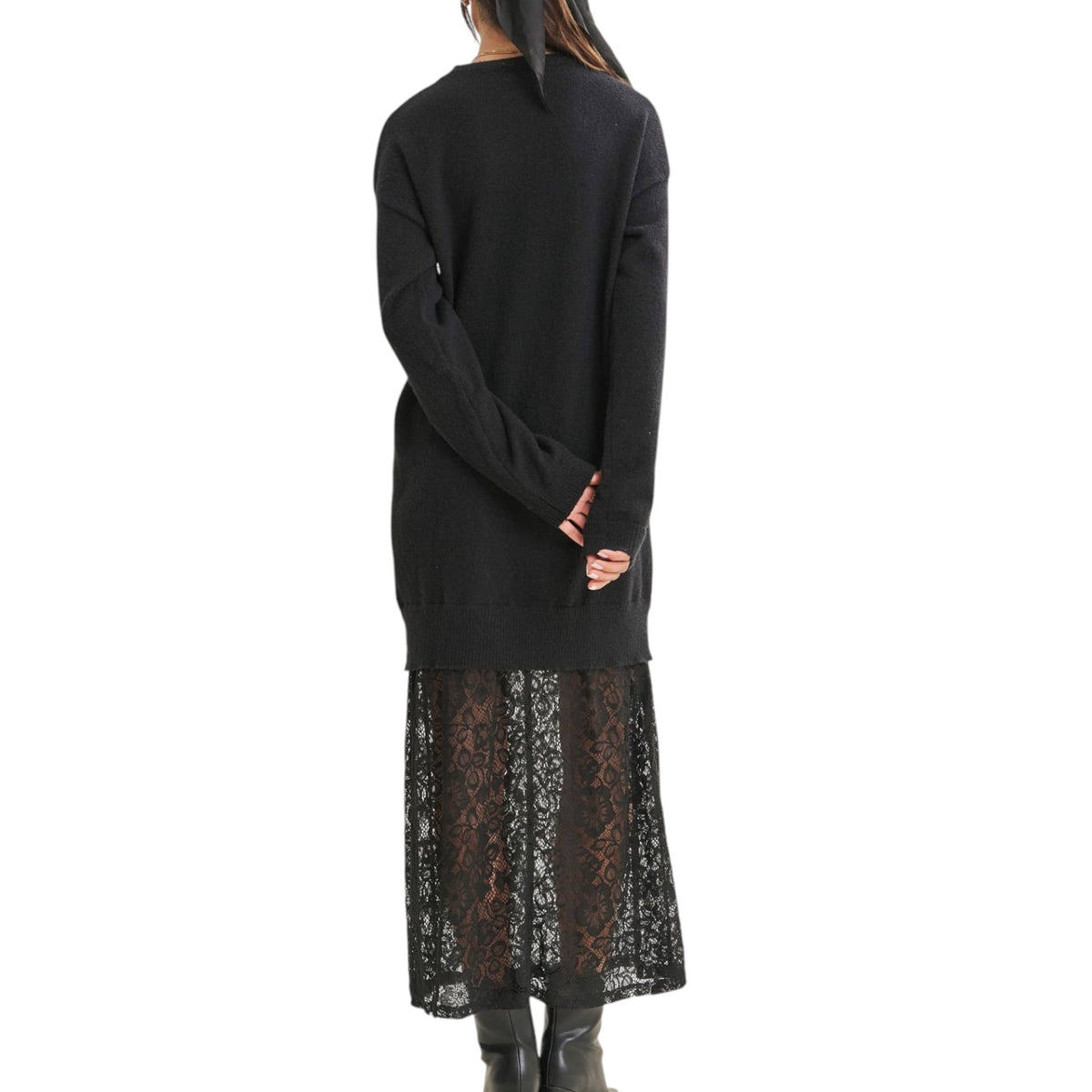 A model shown from the back wearing a black knit long-sleeve sweater over a black lace midi skirt, paired with black boots, against a solid white background.
