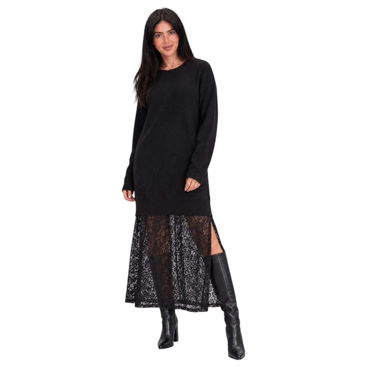 A woman modeling a black long-sleeve knit sweater dress with a sheer black lace overlay skirt, paired with black knee-high boots, against a plain white background.