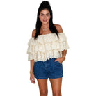 Woman wearing a cream off-shoulder lace top and blue denim shorts on a white background